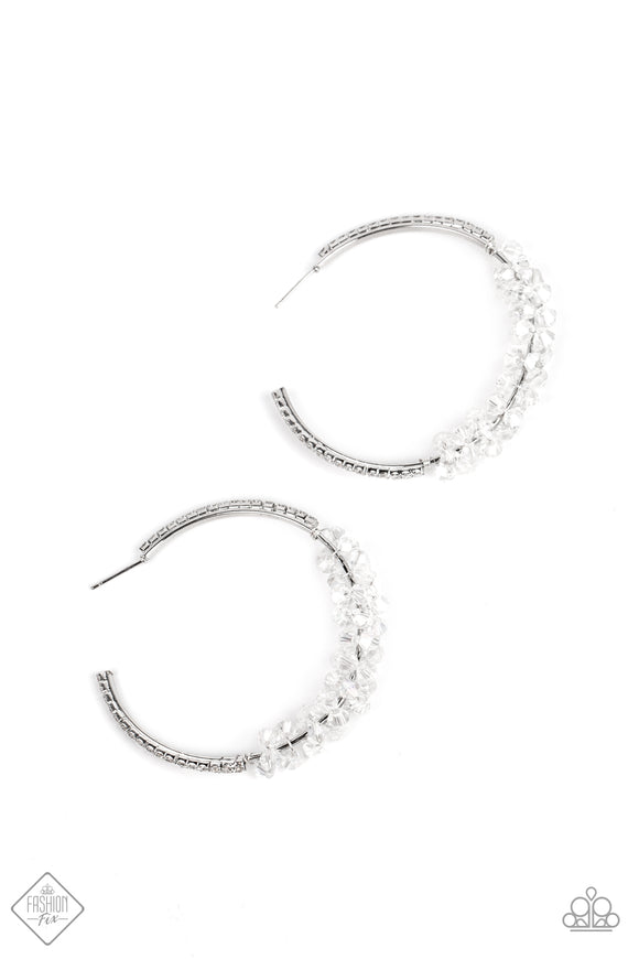 Clusters of transparent crystal-like beads gather along the bottom edge of a silver hoop, adding bubbly effervescence to the classic design. Tiny white rhinestones line the outer edge of the silver hoop, emphasizing the iridescent shimmer that coats the crystal beads. Earring attaches to a standard post fitting. Hoop measures approximately 2” in diameter.  Sold as one pair of hoop earrings.