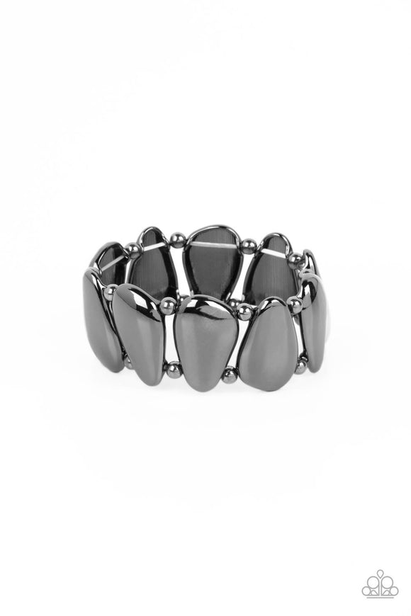 Pear-shaped plates of gunmetal are threaded along stretchy bands and separated by small gunmetal beads as they wrap around the wrist. Each plate features a rounded surface, emphasizing the metallic sheen emanating from the polished prehistoric design.  Sold as one individual bracelet.