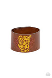 A thick band of brown leather is stamped with the upbeat message, "Good Vibes Only," in a vibrant shade of Primrose Yellow. Vine-like patterns bloom around the curling font, creating a paisley pattern tinted in pink. Features an adjustable snap closure.  Sold as one individual bracelet.