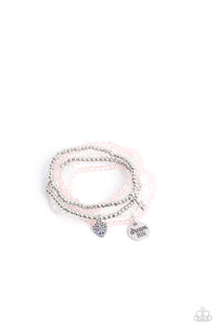 Reflective pink, defaced silver, reflective white, and smooth silver beads wrap around stretchy bands, and combine into a colorful stack along the wrist. The reflective, pink-beaded bracelet features a silver pendant with the phrase "dream BIG" stamped on it, while a defaced, silver-beaded bracelet features a silver star charm. Hanging from smooth, silver beads, a heart charm embossed with iridescent rhinestones adds a shimmery detail to the stack, resulting in a youthful, dreamy design. 