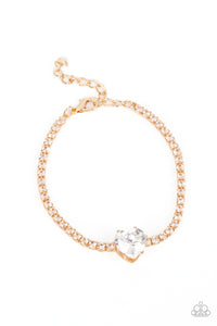 An oversized white heart-shaped gem, set in an airy, pronged gold fitting, glitters at the center of a blinding row of dainty, glassy white rhinestones set in square gold fittings, resulting in a flirtatious sparkle around the wrist. Features an adjustable clasp closure.  Sold as one individual bracelet.