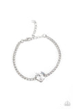 An oversized white heart-shaped gem, set in an airy, pronged silver fitting, glitters at the center of a blinding row of dainty, glassy white rhinestones set in square silver fittings, resulting in a flirtatious sparkle around the wrist. Features an adjustable clasp closure.  Sold as one individual bracelet. 