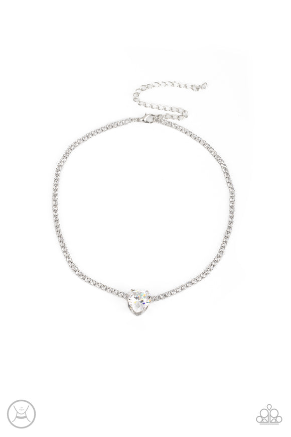 An oversized white heart-shaped gem, set in an airy, pronged silver fitting, glitters at the center of a blinding row of dainty, glassy white rhinestones set in square silver fittings, resulting in a flirtatious sparkle around the neckline. Features an adjustable clasp closure.  Sold as one individual choker necklace. Includes one pair of matching earrings.