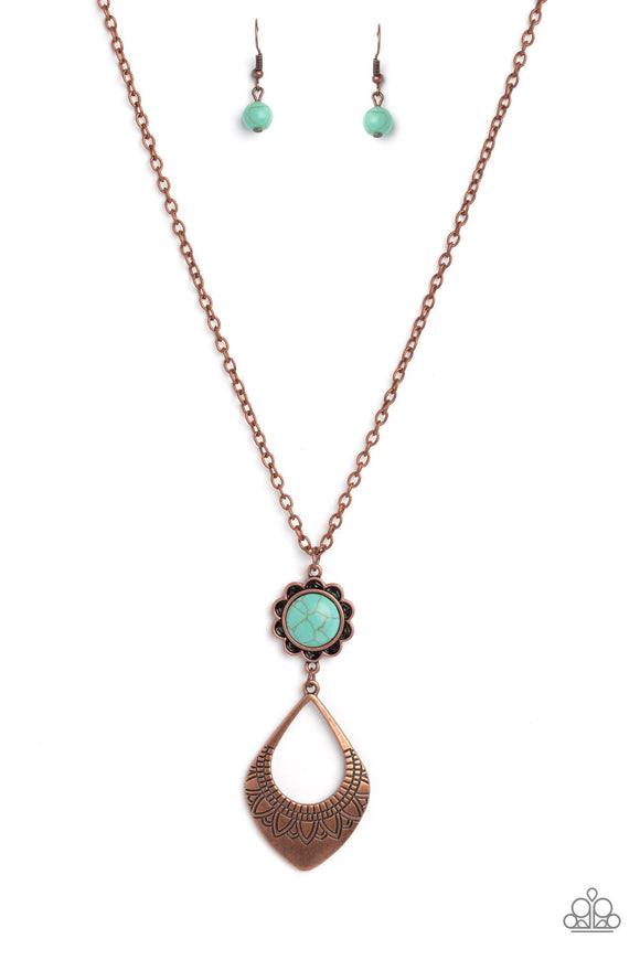 Dangling from an elongated, copper link chain, two whimsical, interconnected shapes coalesce down the chest. An oversized turquoise stone, wrapped in a copper floral frame swings as the uppermost shape above an oversized, airy, copper spade-like frame creating a free-spirited finish. Stamped floral cutouts embellish along the lower curve of the teardrop-like frame for additional artisanal detailing.  As the stone elements in this piece are natural, some color variation is normal. 