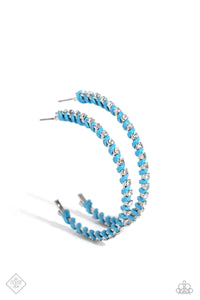 The outer edge of an oversized silver hoop is lined with classic white rhinestones, scattering sparkle in every direction. A strand of blue cording intricately twists and weaves in between the glitzy gems, adding a fearless pop of color to the design. Earring attaches to a standard post fitting. Hoop measures approximately 2″ in diameter.  Sold as one pair of hoop earrings.