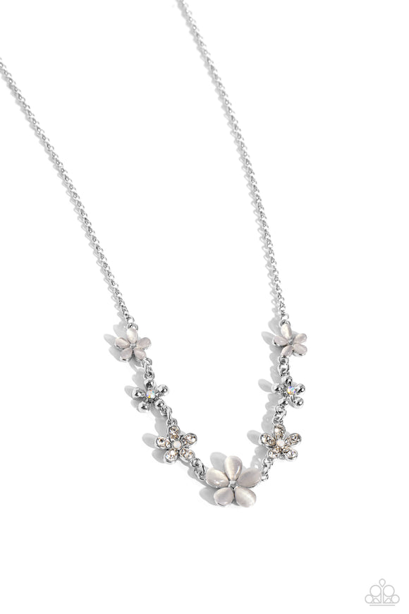 White cat's eye stone petals bloom from silver stud centers, linking into various sizes of ethereal blossoms below the collar on a dainty silver chain. Silver-studded petals bloom from iridescent rhinestones, while dainty white rhinestone petals bloom from opalescent centers finishing the design off with additional eye-catching florals, adding dazzling dimension. Features an adjustable clasp closure. Due to its prismatic palette, color may vary.