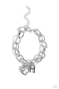 A simple collection of silver charms — including a white rhinestone heart pressed in a silver frame and a sleek letter "H" — dance from a chunky silver chain around the wrist, creating a sentimental fringe. Features an adjustable clasp closure.  Sold as one individual bracelet.