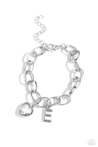 A simple collection of silver charms — including a white rhinestone heart pressed in a silver frame and a sleek letter "E" — dance from a chunky silver chain around the wrist, creating a sentimental fringe. Features an adjustable clasp closure.  Sold as one individual bracelet.