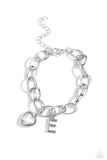 A simple collection of silver charms — including a white rhinestone heart pressed in a silver frame and a sleek letter "E" — dance from a chunky silver chain around the wrist, creating a sentimental fringe. Features an adjustable clasp closure.  Sold as one individual bracelet.