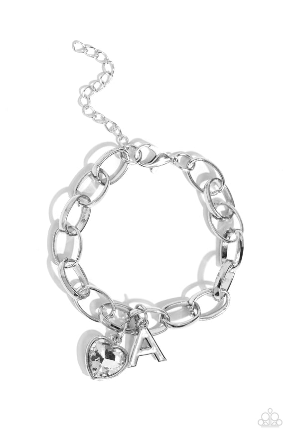 A simple collection of silver charms — including a white rhinestone heart pressed in a silver frame and a sleek letter 