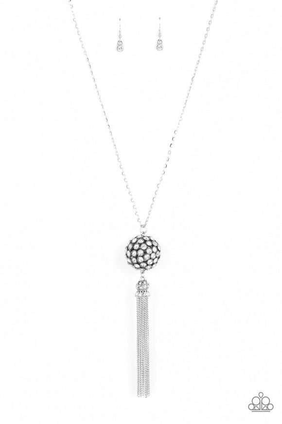 Infused with silver studded fittings, a glittery collection of sparkly white rhinestones coalesce into a dramatic pendant at the bottom of a lengthened silver chain. Capped in a rhinestone dotted frame, a shimmery silver tassel streams out from the blinding pendant for a flirtatious finish. Features an adjustable clasp closure.  Sold as one individual necklace. Includes one pair of matching earrings.